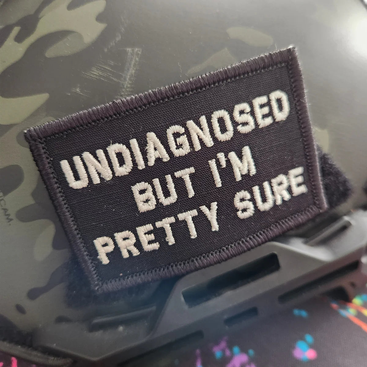 Patch with text 'undiagnosed but I'm pretty sure' on a helmet with camouflage pattern