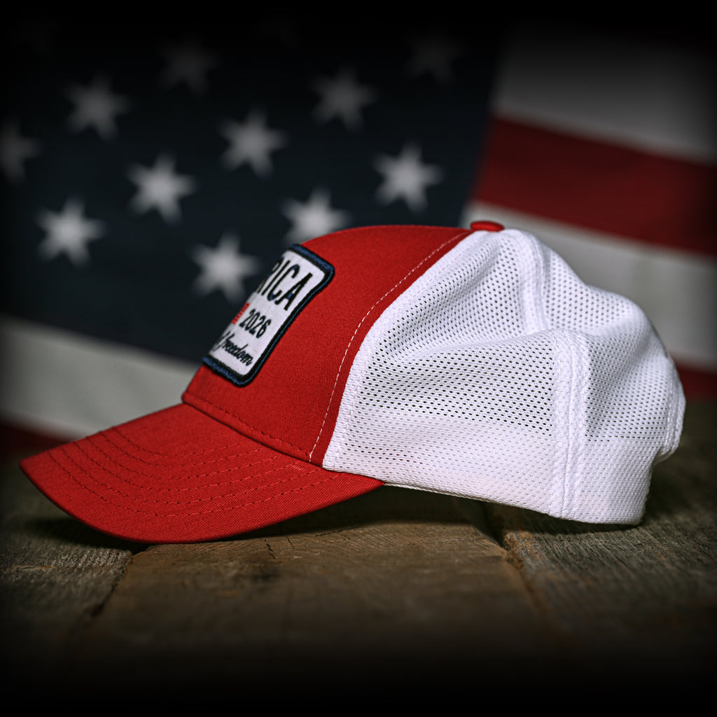 Red and white trucker with a patch on a wooden surface with an American flag in the background