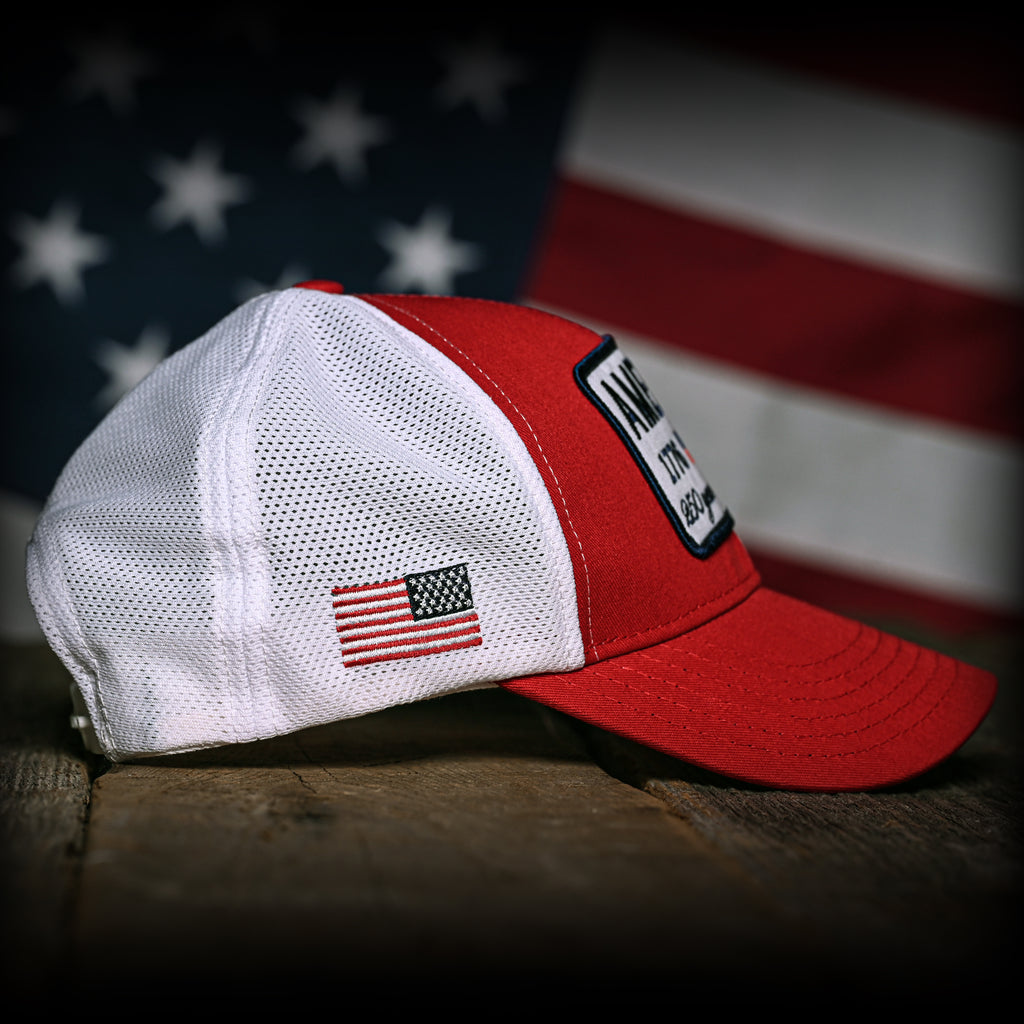 Red and white trucker with American flag design on a wooden surface with an American flag in the background