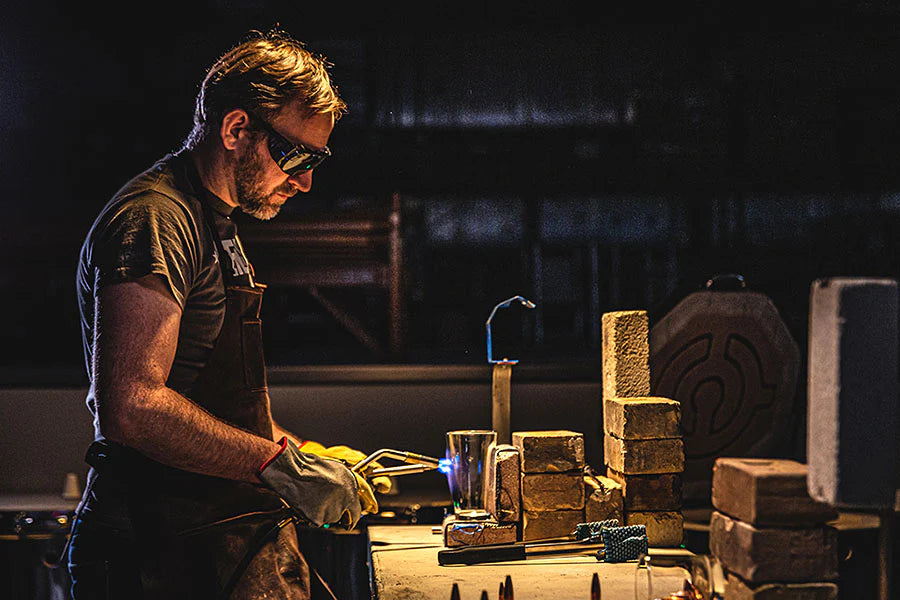 Man working with a blowtorch to craft glassware.