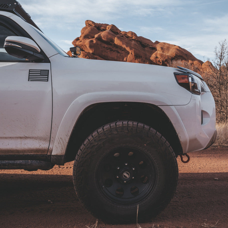 White pickup truck on a dirt road with an American flag vehicle magnet in reverse orientation