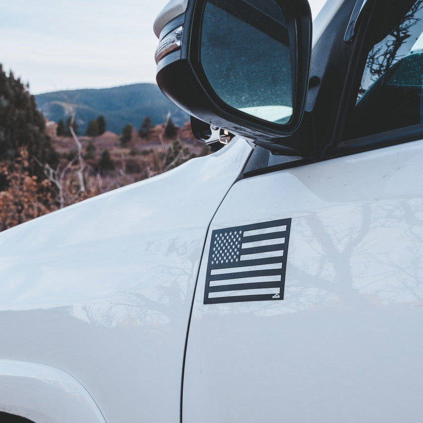 White car with an American flag decal on a mountain road
