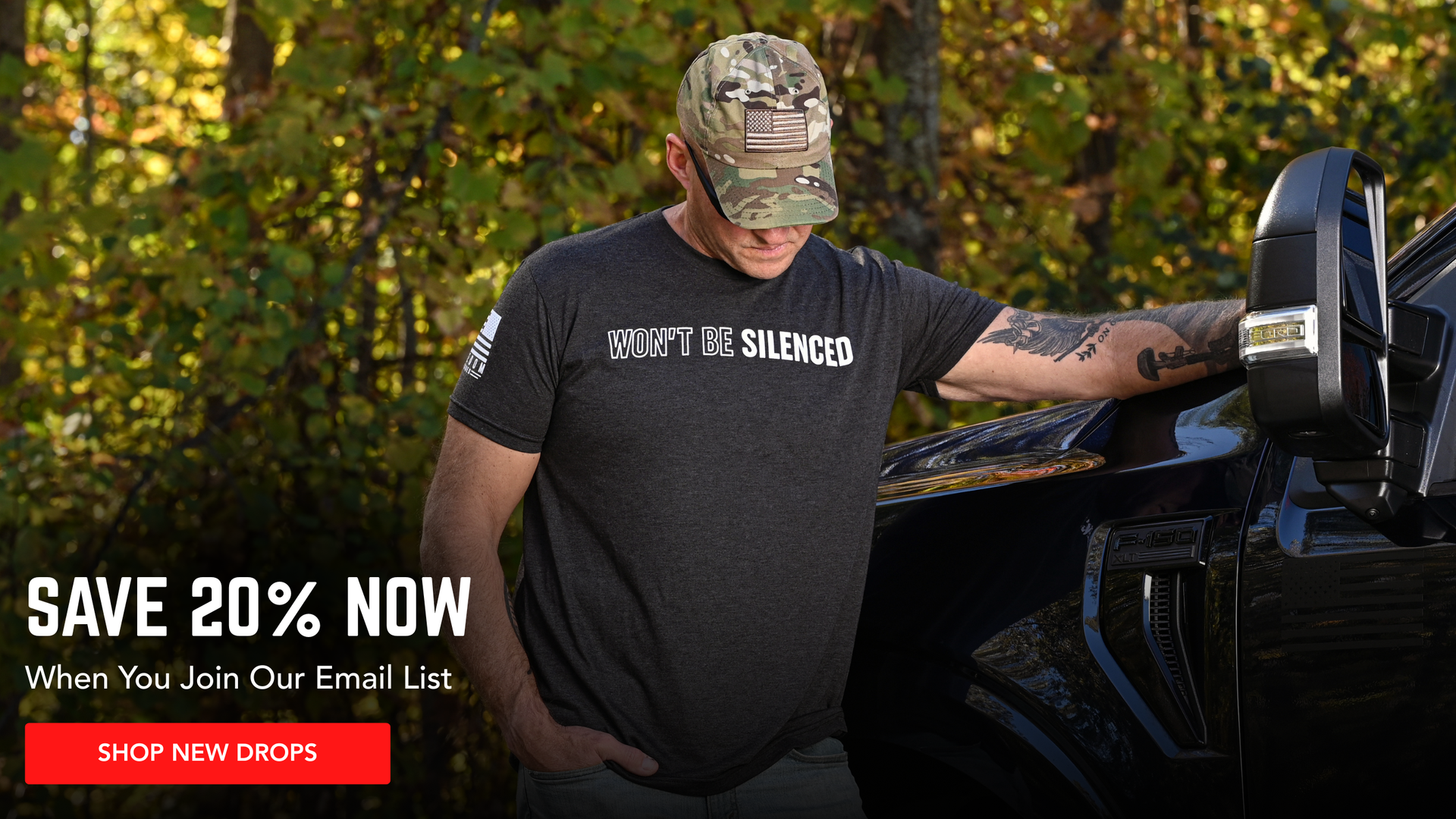 Man wearing a patriotic "Won't Be Silenced" black t-shirt and promotion to save 20% with email signup.