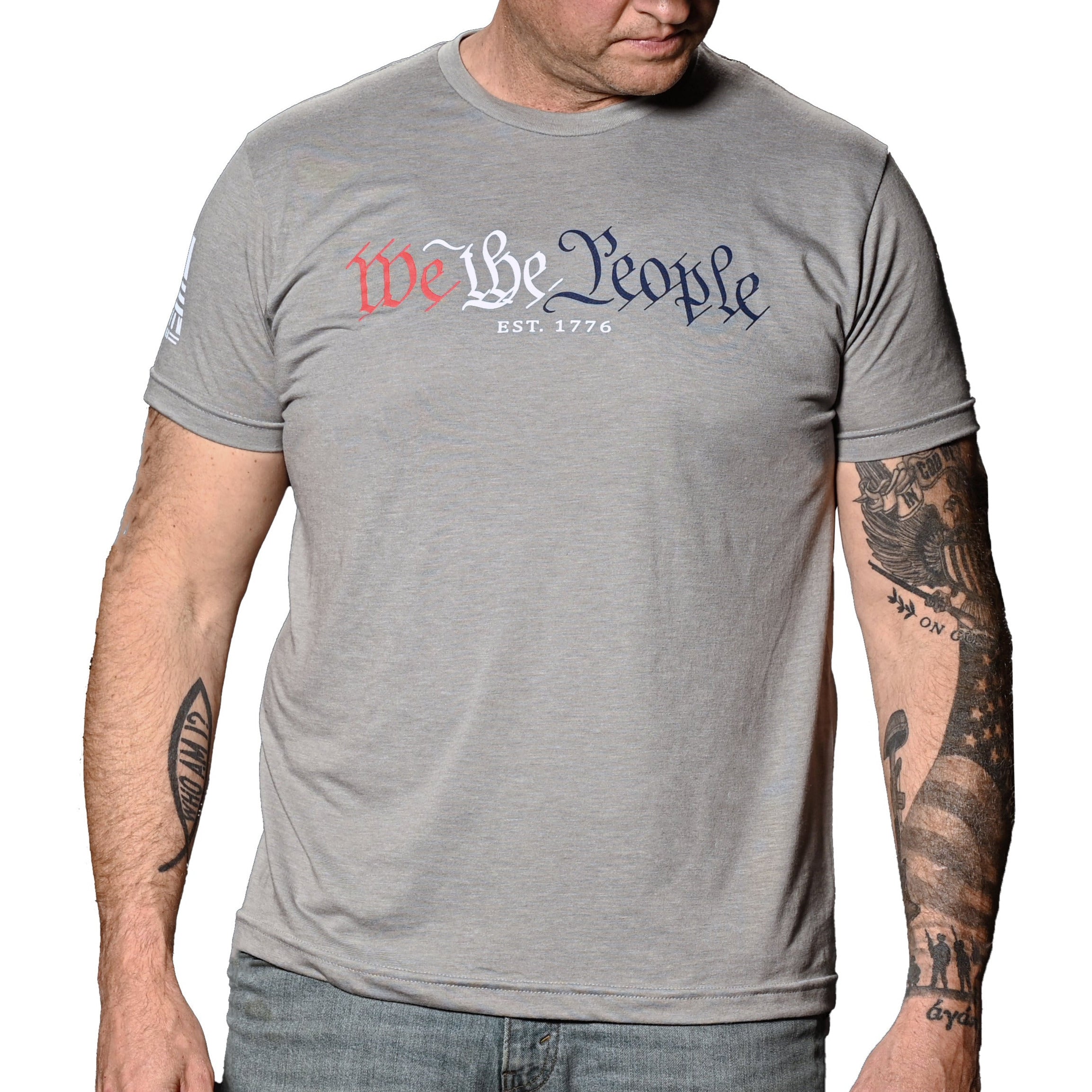 A man wearing the patriotic 'We The People' gray crew neck t-shirt with text in red and blue. (front view)