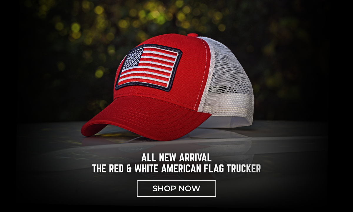 A red and white trucker cap with an American flag patch on the front, displayed against a dark, blurred background with a 'SHOP NOW' promotional overlay.