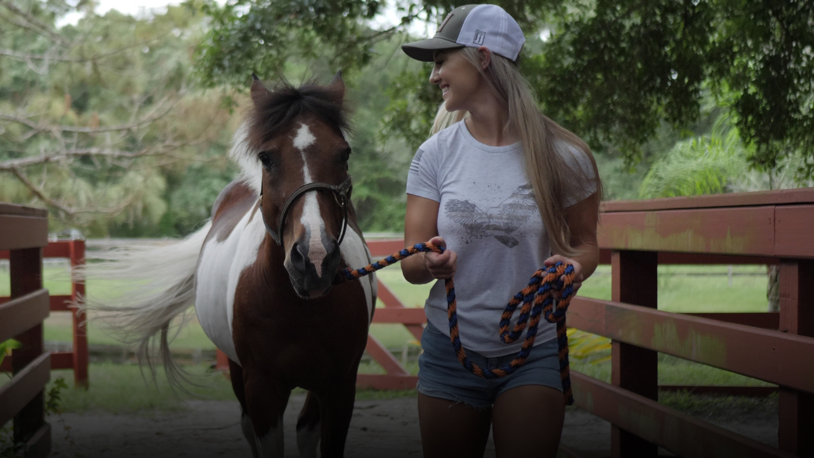 Woman wearing a patriotic tshirt and leading a horse