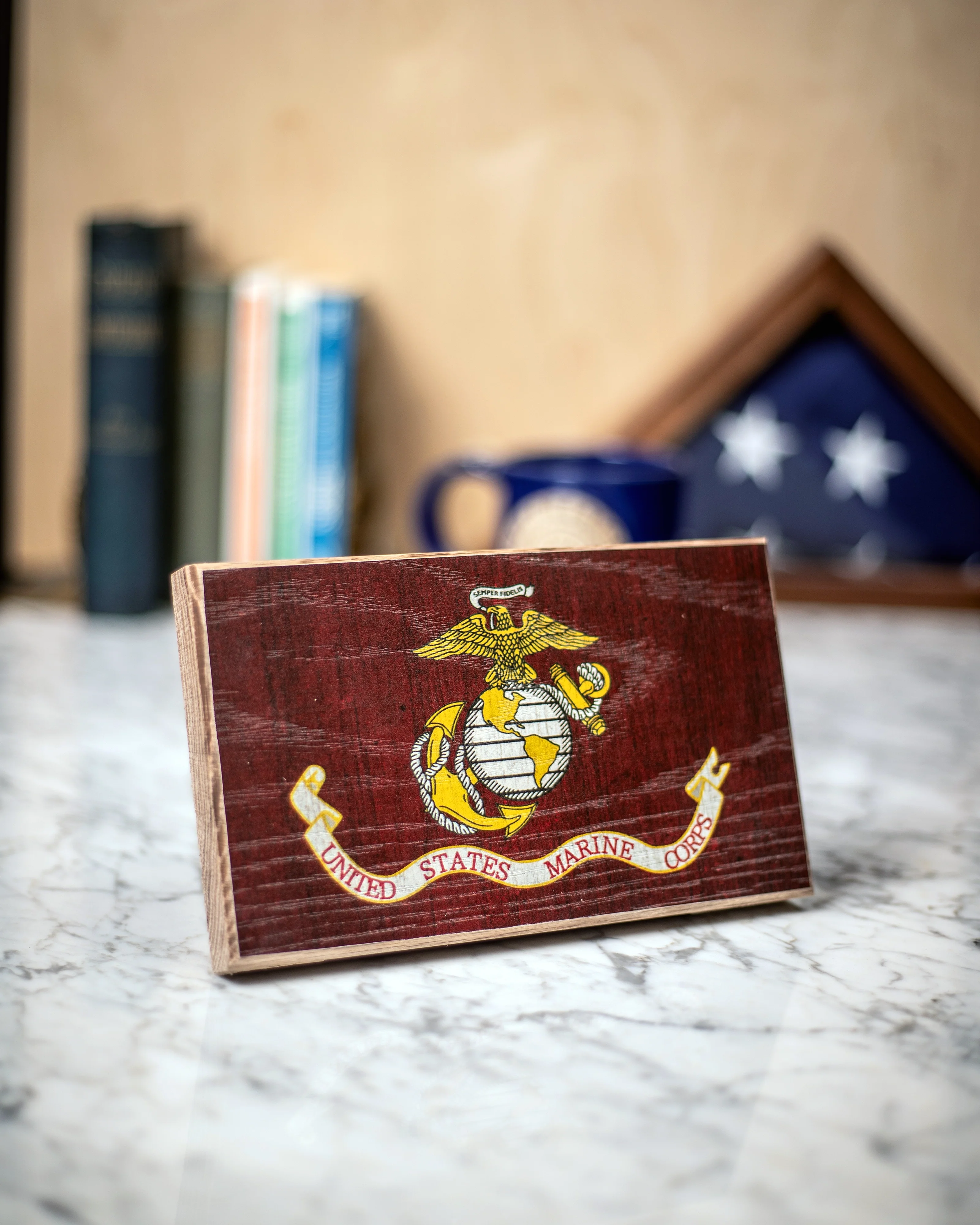 Wooden plaque with U.S. Marine Corps emblem on a marble surface.